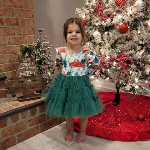 Girls boutique dress with layered and spliced green tulle, print includes vintage red truck hauling Christmas trees.  Shoulder has angel ruffle, back ties at neckline.