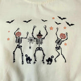 Dancing skeletons adorn this fun Halloween themed buttercream kids long sleeve top.
