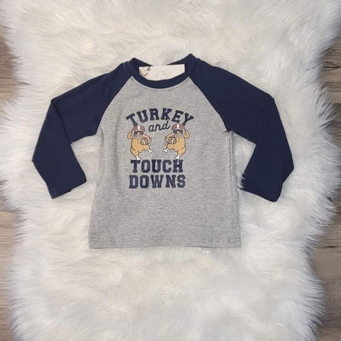 Boys baseball style top in grey with blue sleeves.  Front says "Turkey and touchdowns" and has two turkeys wearing helmets carrying footballs.