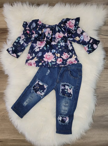 Navy blue floral ruffle top with distressed, patched denim jeans.