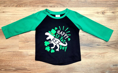 Boys baseball style top.  Black body with green sleeves and "Happy St. Pat-Rex Day" with a dinosaur wearing a green hat on the front.