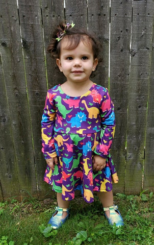 Long sleeve purple girls dress with bold colored dinosaur pattern.